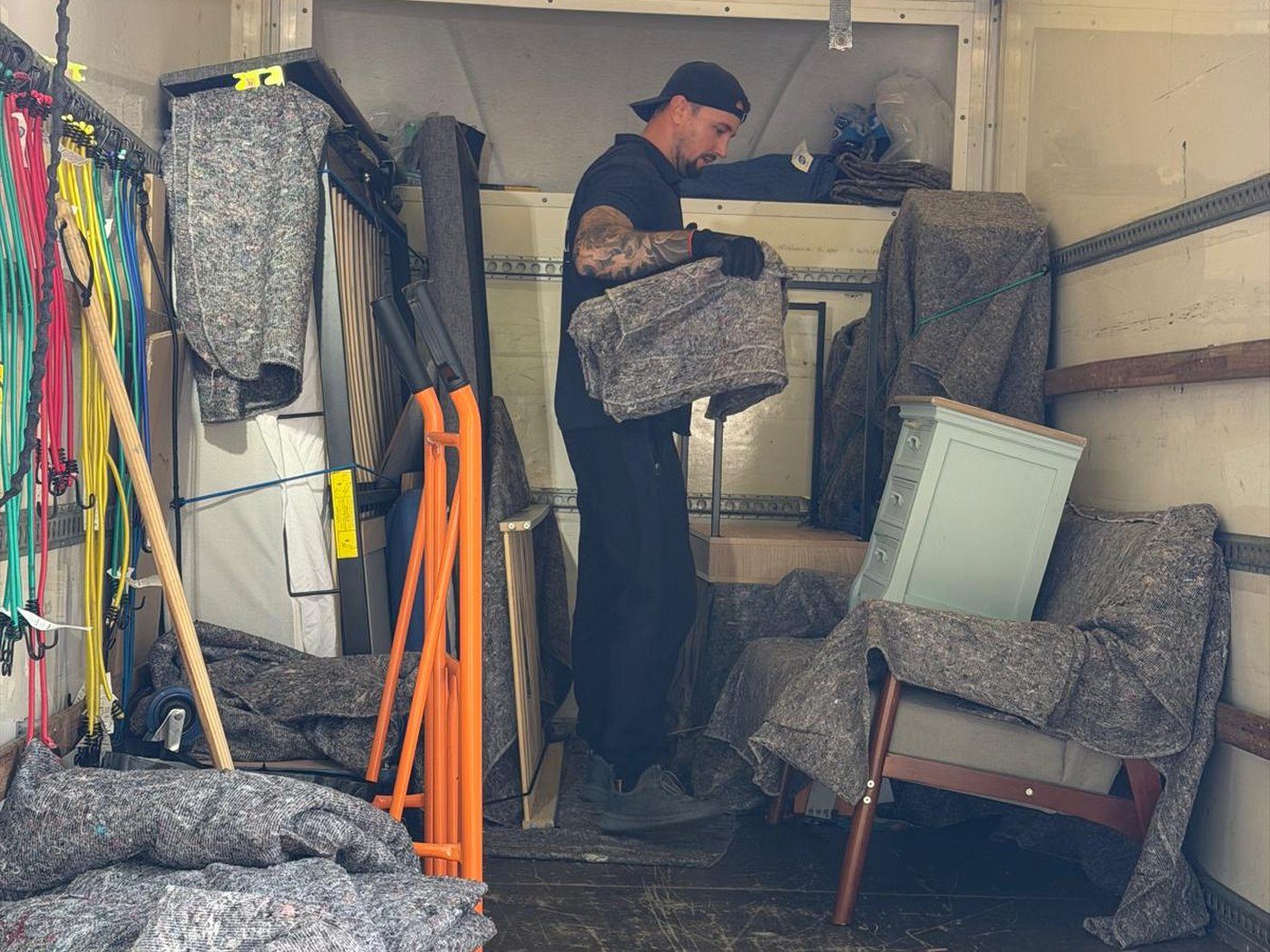 Removals crew member lifting a wrapped item inside the van